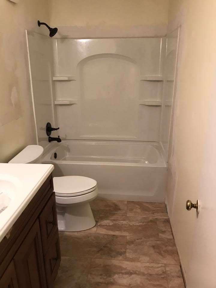 Finished bathroom with new tub, shower surround, fixtures and tile floor