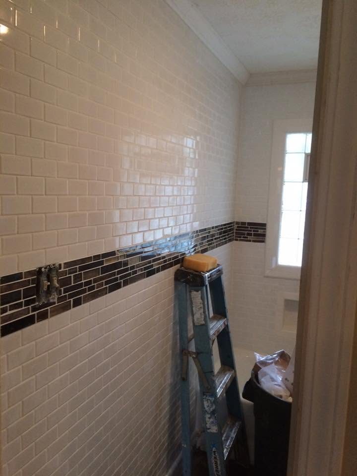 Finished white subway tile walls with dark glass accent band