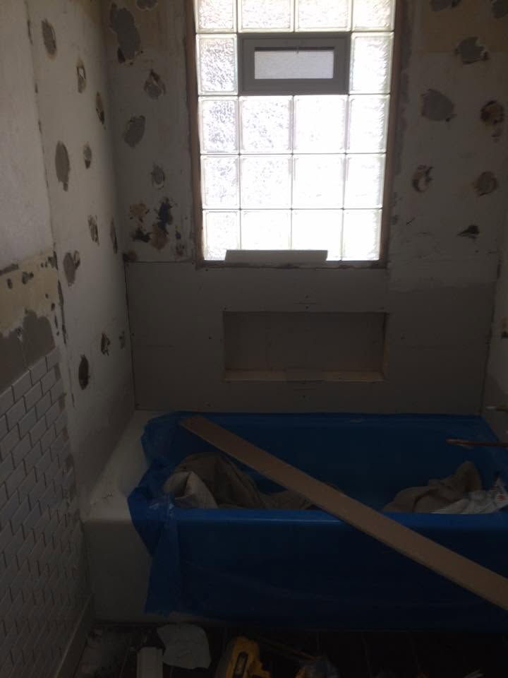 Bathroom walls patched and prepped for tile with tub covered in plastic