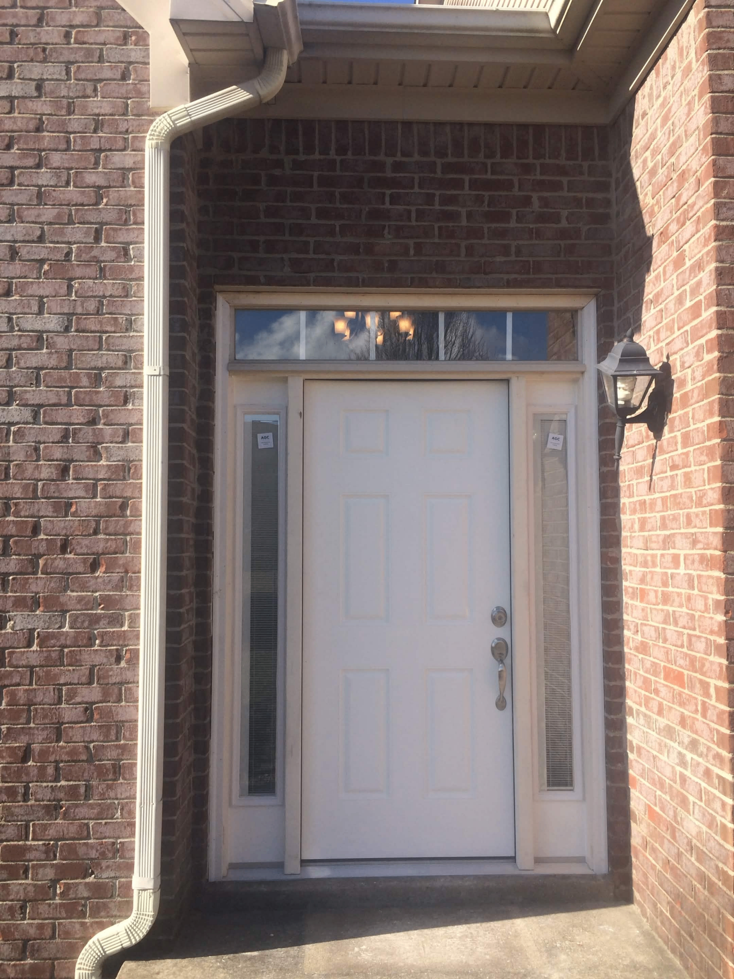 New white front door with sidelights and transom installed in brick entryway