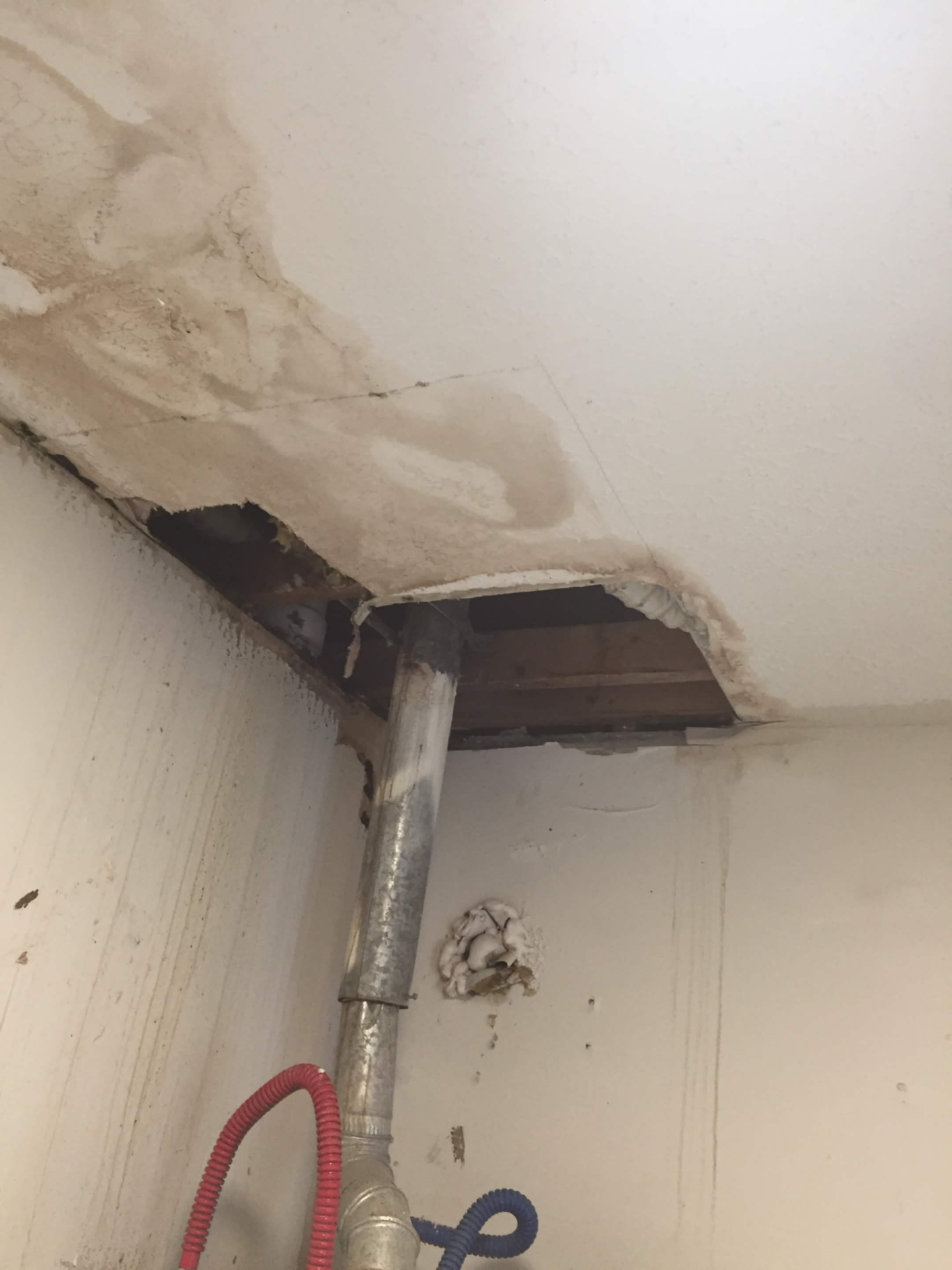 Water-damaged ceiling before repair, showing exposed framing and stained drywall